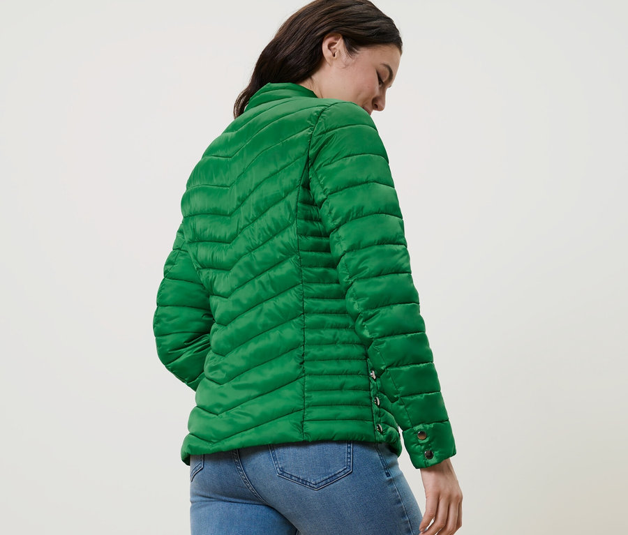 Frau trägt Steppjacke und Jeans.