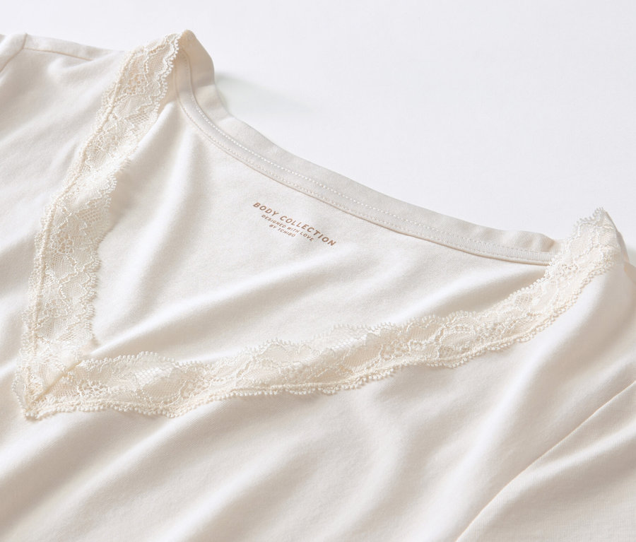 Detailansicht eines cremefarbenen Pyjamas mit Alloverprint und V-Ausschnitt mit Spitzenbesatz.