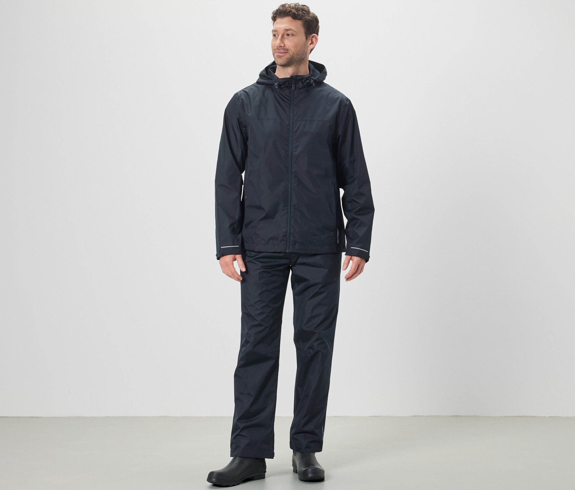 Ein Mann trägt eine Regenjacke und eine Unisex-Regenhose.