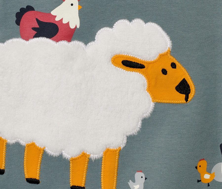 Detail eines Kinder-Langarmshirts mit Schaf-, Hahn- und Kükenmotiv.