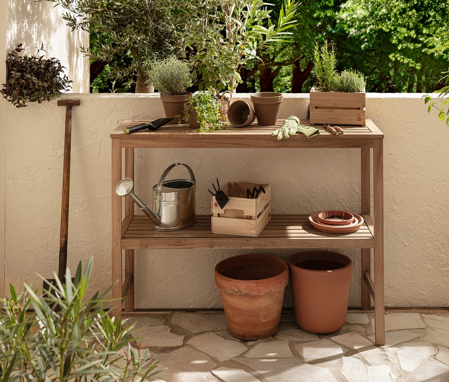 Auf einer Terrasse stehen eine große Konsole mit 2 Ebenen »Lenja« und ein dekoratives Hochbeet »Elin« mit abnehmbarem Anzuchtaufsatz. Auf der Konsole befinden sich Blumentöpfe, Gartengeräte und eine Gießkanne.