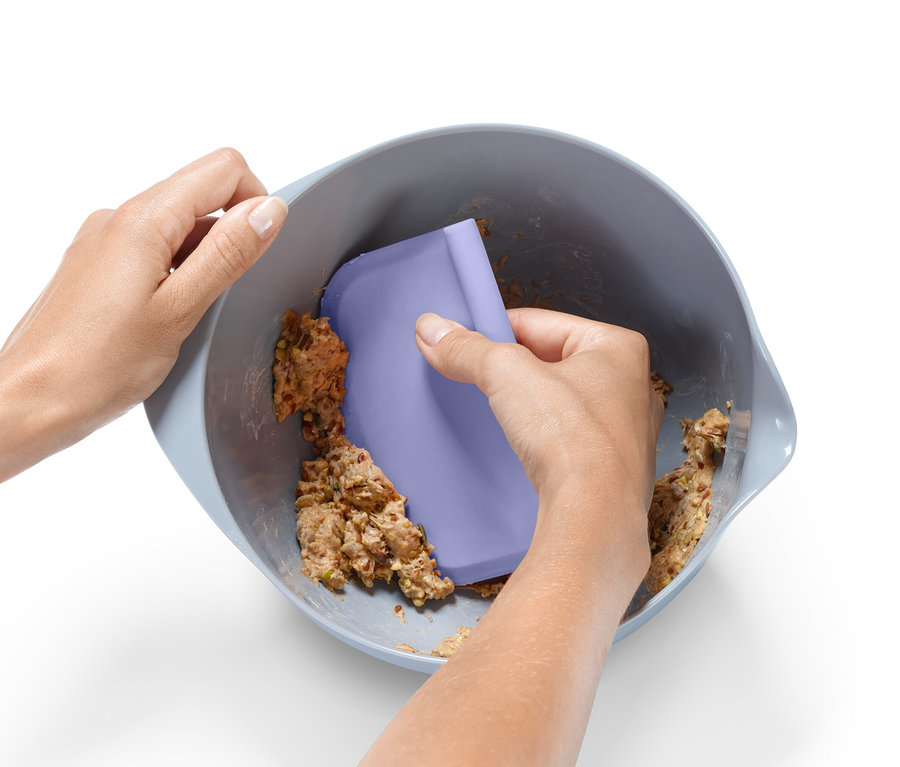 Person verrührt Teig in einer Schüssel mit einem lila Spatel aus dem Backhelfer-Set.