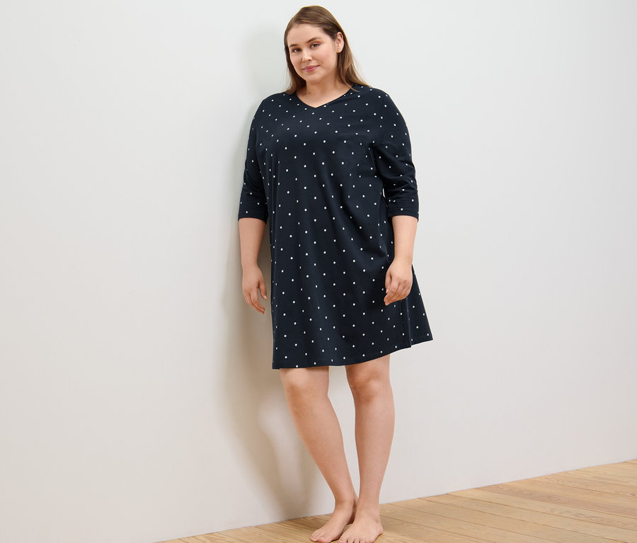 Frau steht und trägt ein Nachthemd.