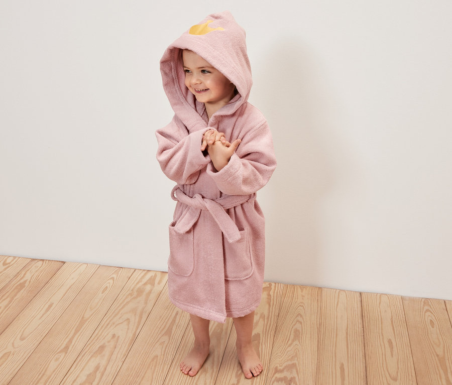 Ein Mädchen trägt einen rosa Kinder-Bademantel, Prinzessin, mit Kapuze.