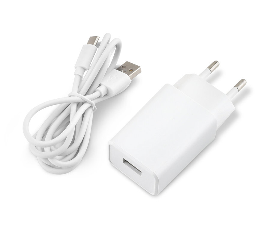 Ein weißer Adapter und ein aufgerolltes USB-Kabel liegen auf einer weißen Oberfläche.