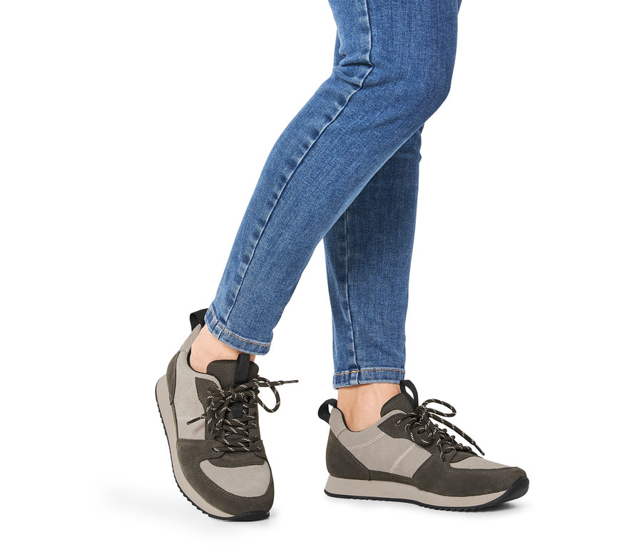 Beine in blauen Jeans, die Veloursleder-Sneaker tragen.