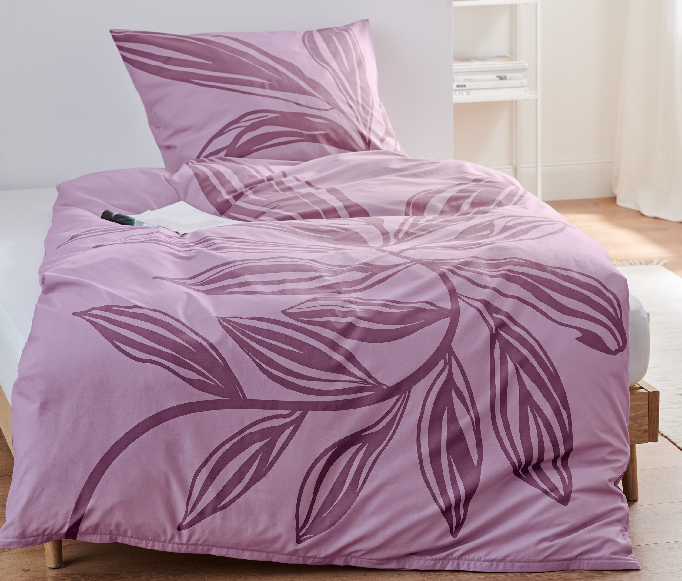 Lila Premium-Baumwoll-Bettwäsche mit Blumenmuster liegt auf einem Bett.