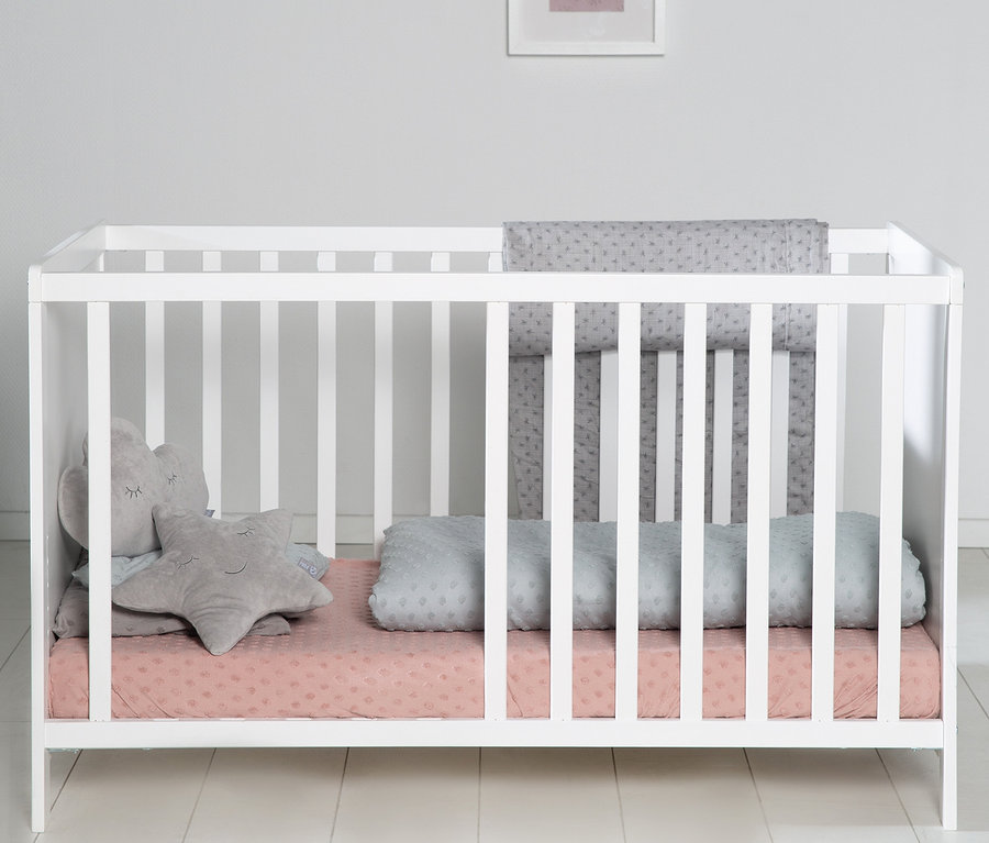 Weißes roba Kinderzimmer-Set Bett mit rosa Spannbetttuch, grauen Kissen und Nestchen.