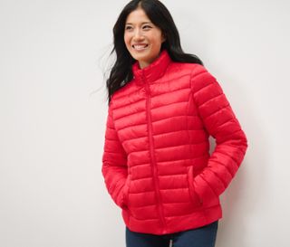 Frau lächelt und posiert in roter Steppjacke.