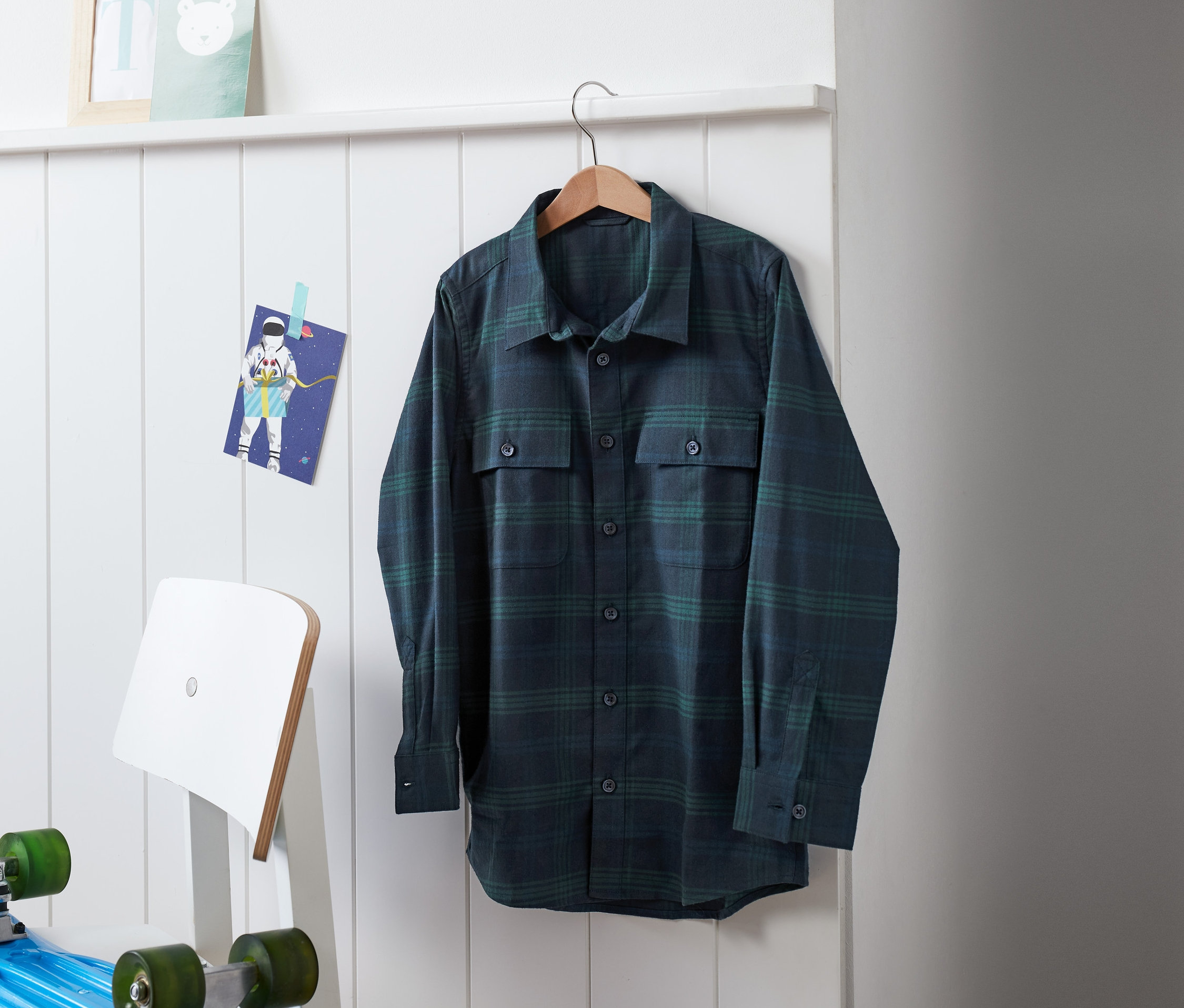 Ein blau-grünes Flanellhemd hängt an einem Kleiderbügel.