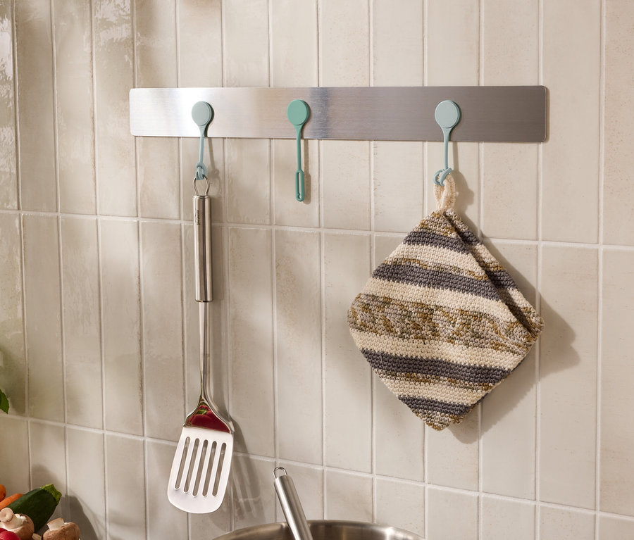 An der Wand hängen Küchenutensilien wie ein Pfannenwender und ein Geschirrtuch an Haken.