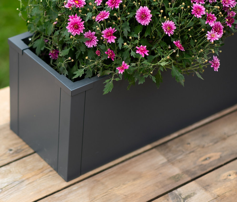 Nahaufnahme eines grauen Pflanzkastens mit rosa Blumen auf einer Holzterrasse. Im Angebot: Pflanzkasten mit Einlegeboden, ca. 27 cm.