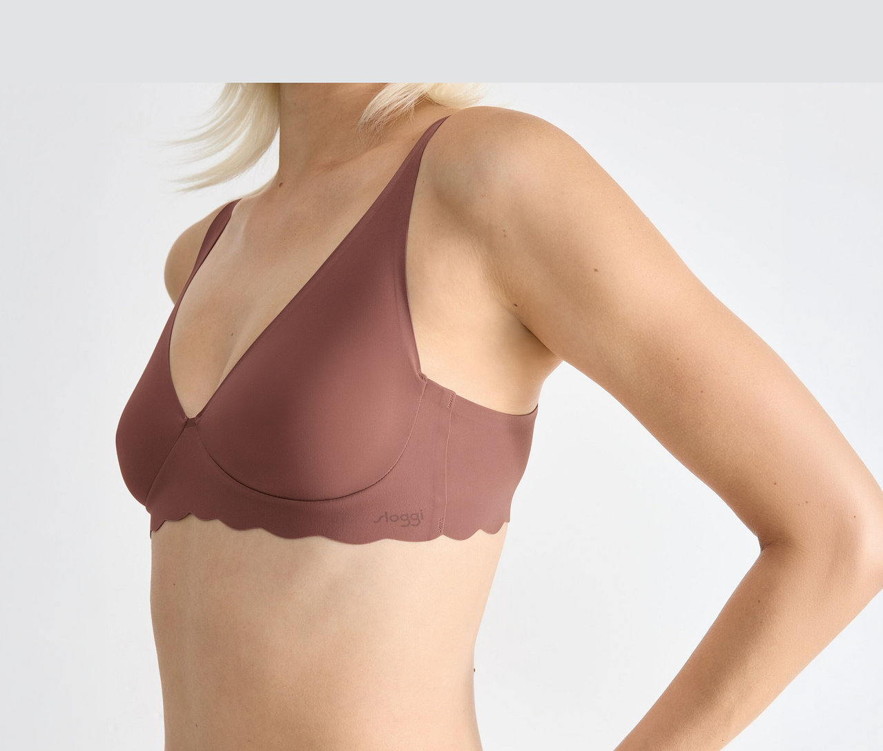 Eine Frau trägt einen rosébraunen sloggi ZERO Microfibre 2.0 Soft Bra mit gewelltem Saum.