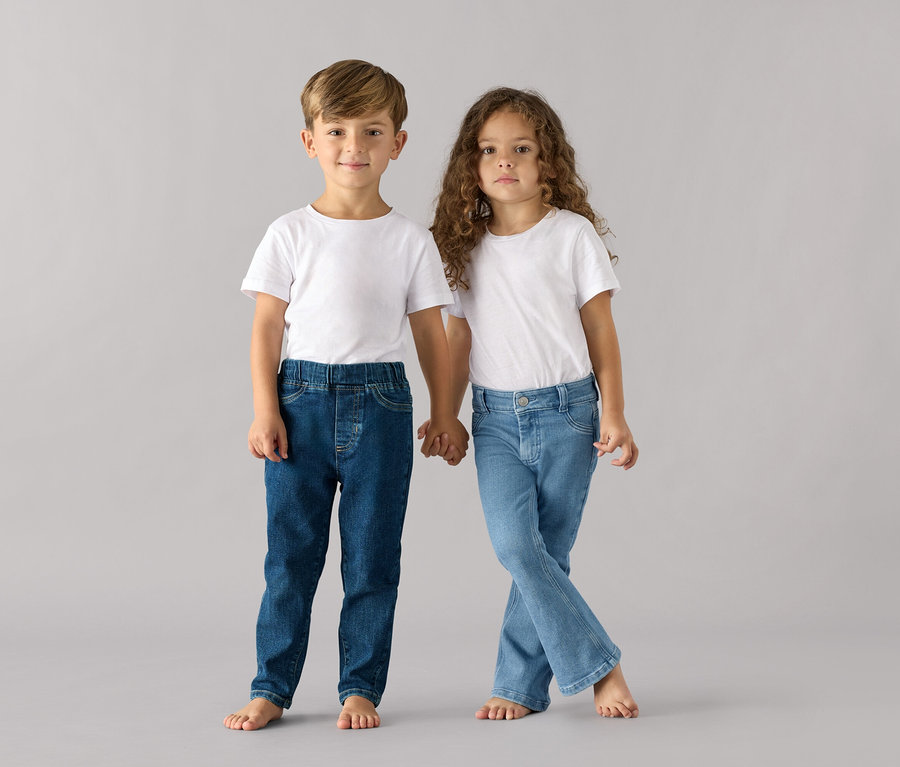 Ein Junge und ein Mädchen halten Händchen und tragen beide weiße T-Shirts und Kinder-Pull-on-Pants – Fit »Luca«.