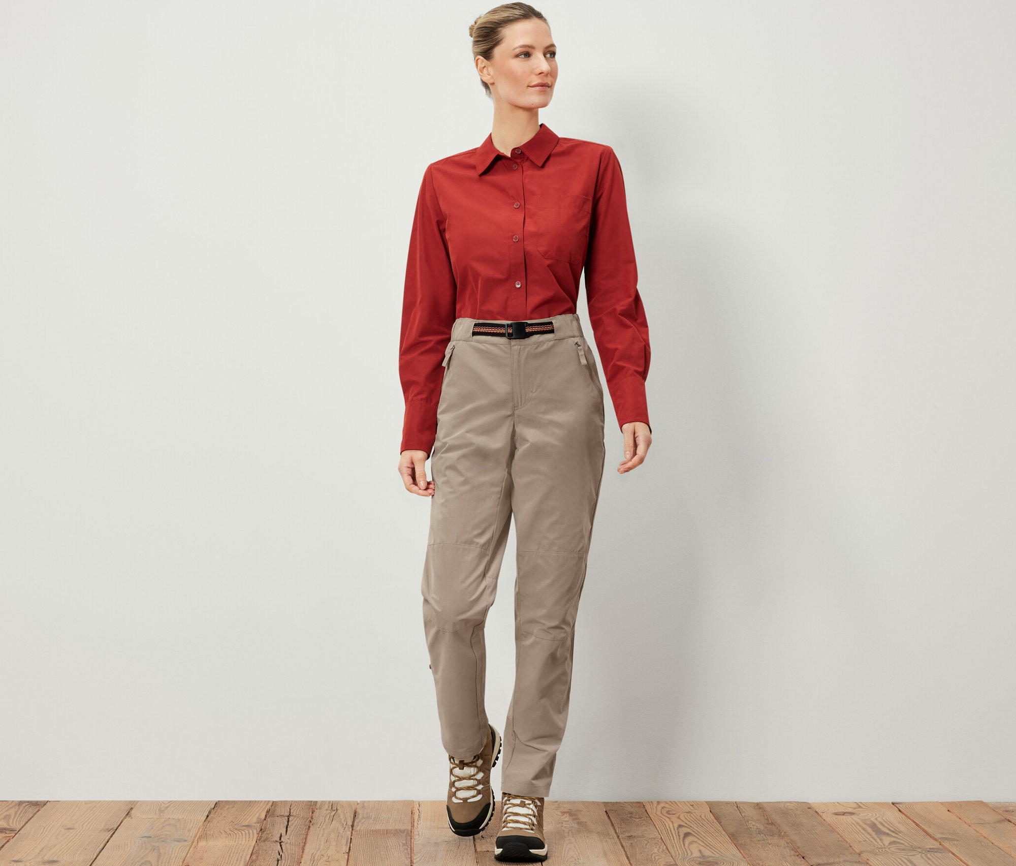 Frau trägt eine Outdoorhose mit Moskito-Schutz, ein braunes Hemd und Wanderschuhe.
