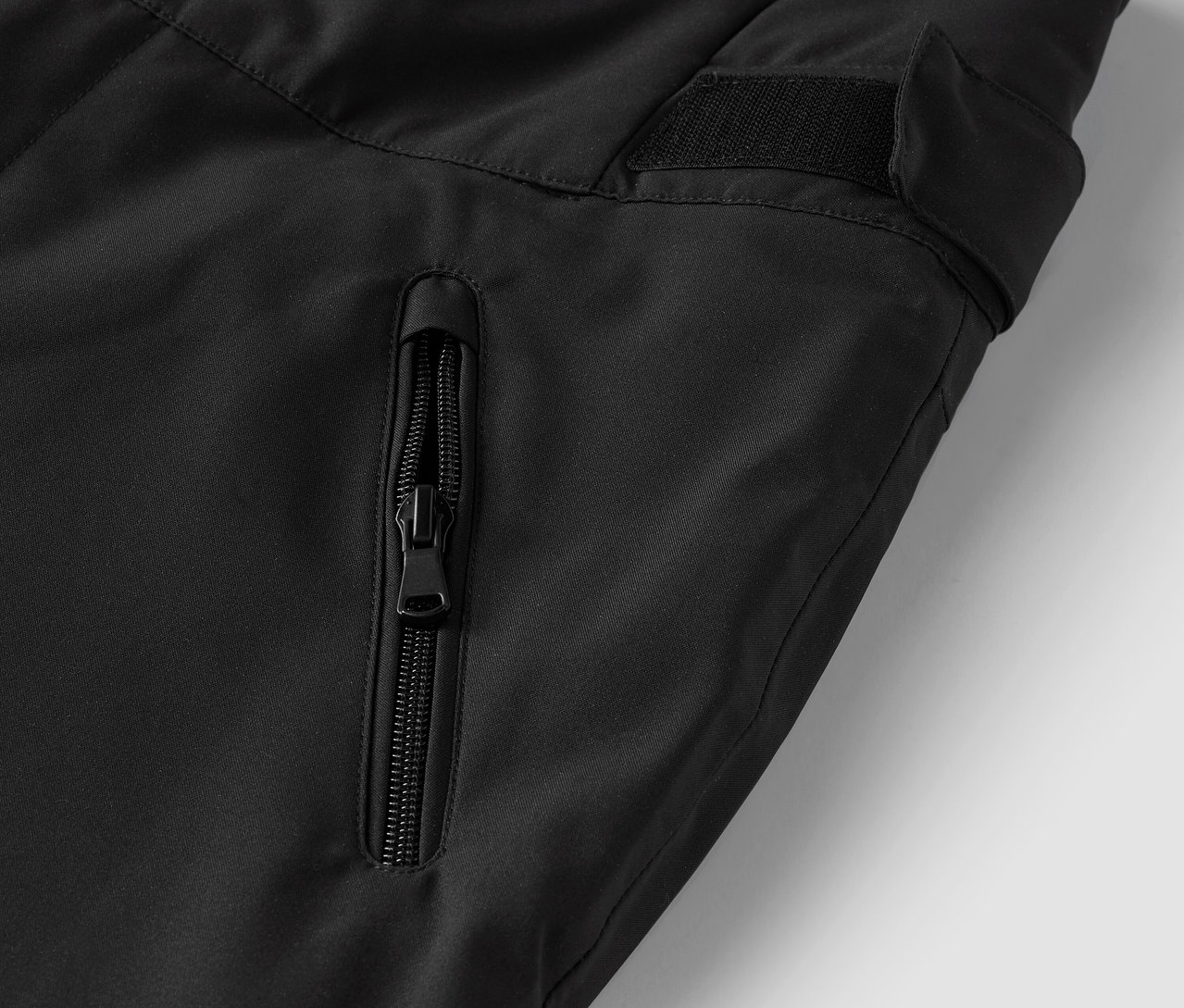 Detail einer schwarzen Hose mit Reißverschlusstasche.