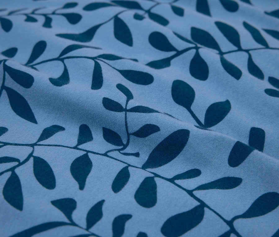 Detailaufnahme eines blauen Stoffes mit dunkelblauem Blätterdruck.