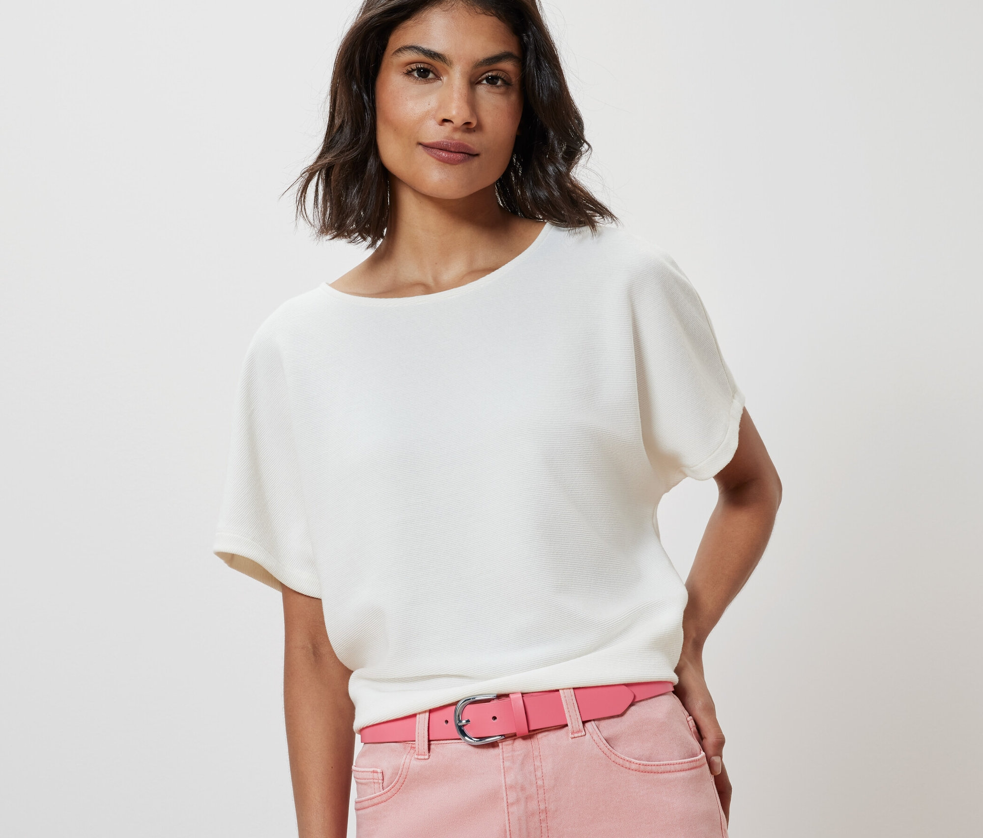 Frau trägt eine weiße Bluse und einen rosa Gürtel.