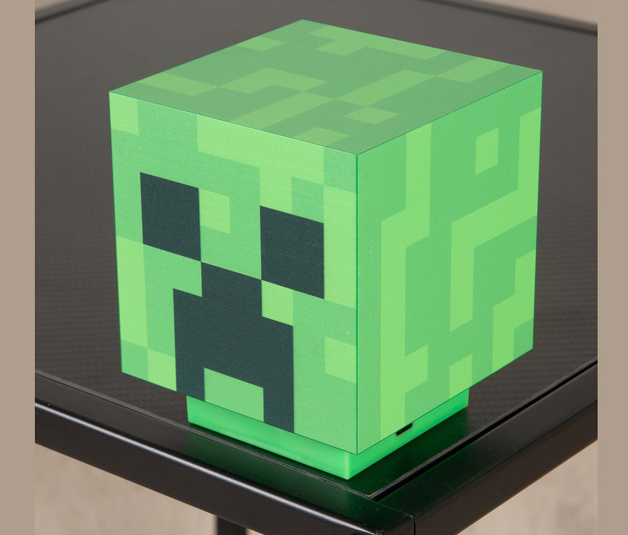 Eine Creeper MINECRAFT LED-Dekoleuchte steht auf einem schwarzen Tisch.