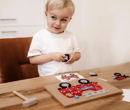 Ein Junge spielt mit dem small foot Hämmerchenspiel, Fahrzeuge der Stadt.