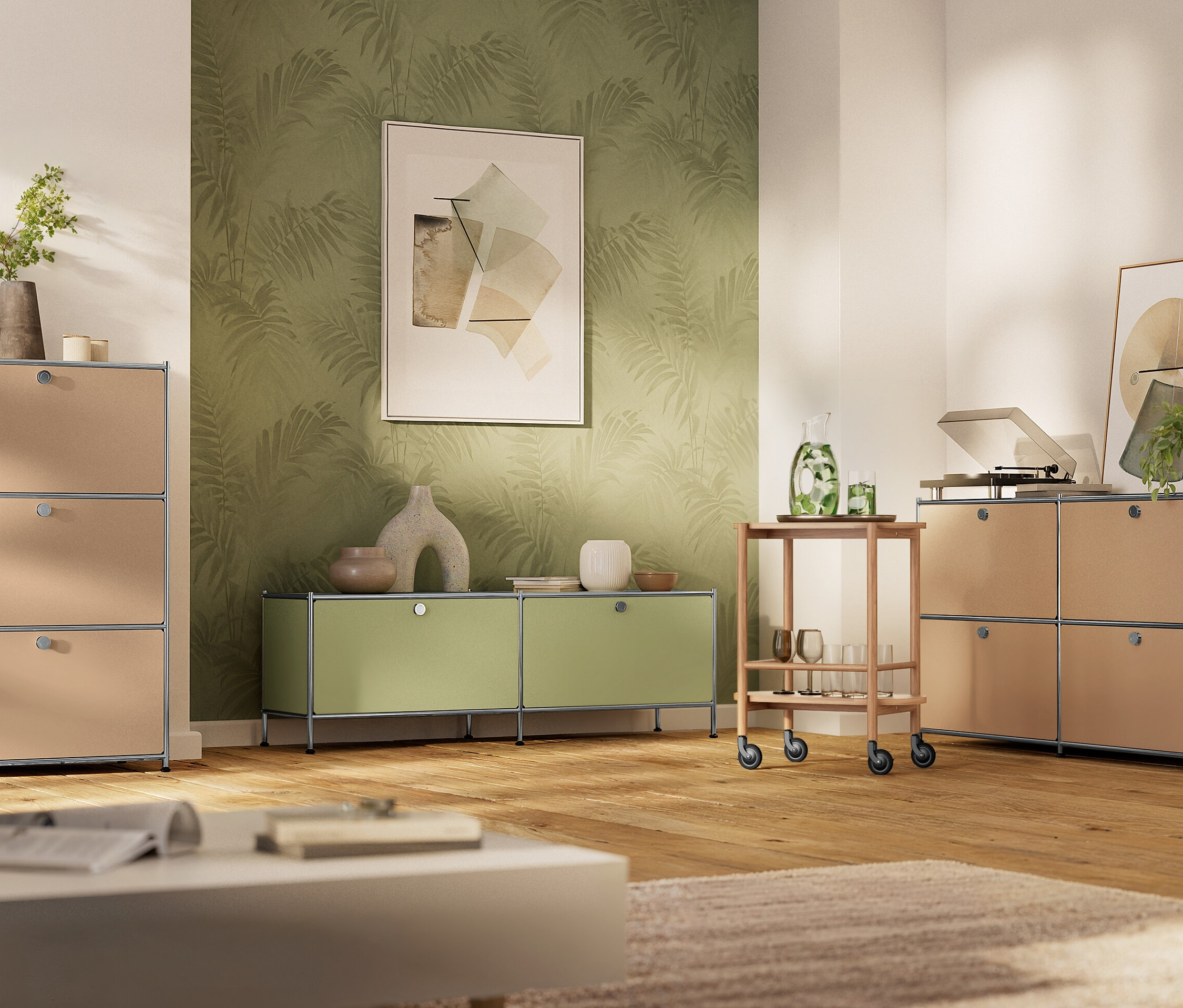 Wohnzimmer mit beigen und lindgrünen USM Möbeln, darunter Regale und ein Servierwagen, auf einem Holzboden.