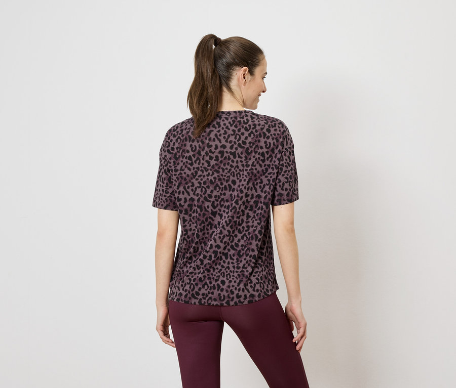 Rückansicht einer Frau mit Pferdeschwanz, die ein braunes Leoparden-T-Shirt und burgunderfarbene Leggings trägt.