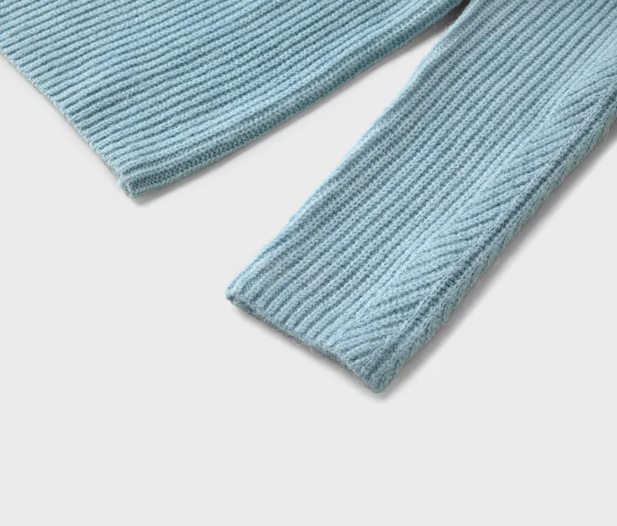 Nahaufnahme eines hellblauen, gerippten Strickpullovers mit Ärmel und Saum auf weißem Grund.