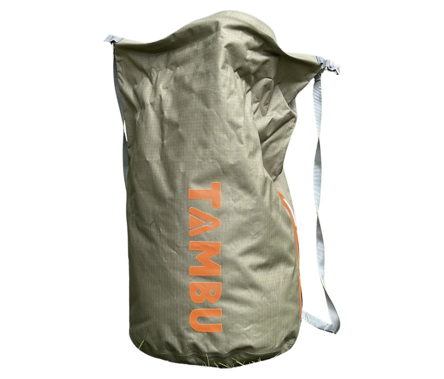 Der Tambu Wasserdichter Packsack »JOLA 80« in Khaki steht auf Gras. Der Markenname ist in Orange aufgedruckt.