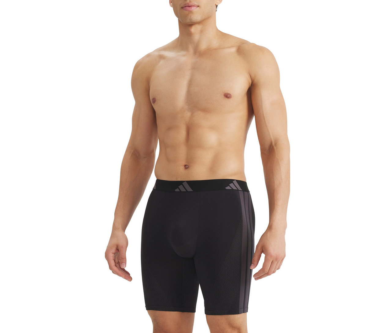 Oberkörperfreier Mann trägt schwarze Boxershorts mit schwarzem Bund und grauem Logo sowie drei grauen Streifen an der Seite.