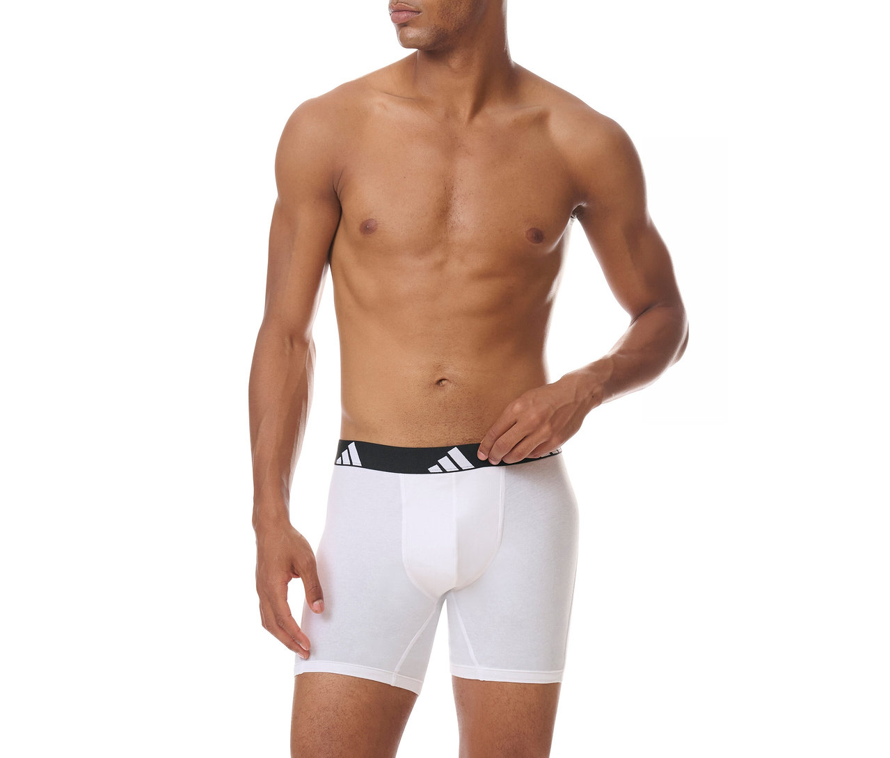 Oben ohne Mann trägt weiße Boxershorts mit schwarzem Adidas-Logo-Bund und passt den Bund mit der rechten Hand an.