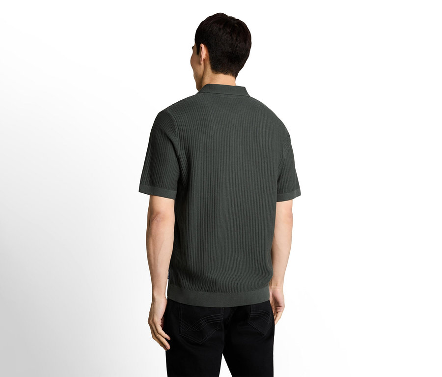 Mann von hinten, trägt ein dunkelgrünes, geripptes Kurzarm-Poloshirt und schwarze Jeans.