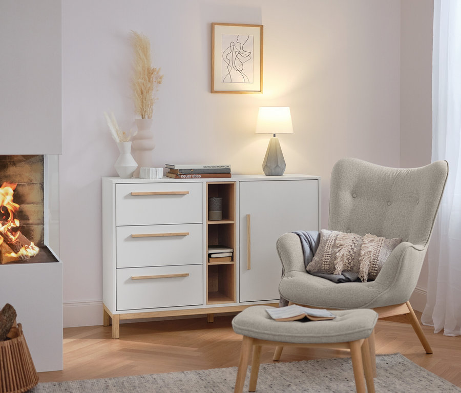 Tischleuchte mit Keramikfuß steht auf einer weißen Kommode im Wohnzimmer.