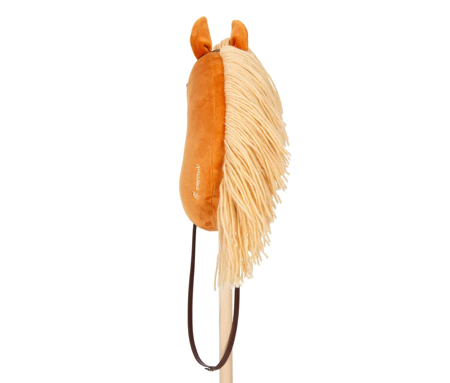 Ein braunes Plüsch-Steckenpferd mit langer, hellgelber Garnmähne und dunkelbraunen Kunstlederzügeln, befestigt an einem hellen Holzstab.