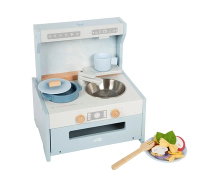 Eine hellblaue und weiße small foot Tabletop-Kitchen mit Topf, Tasse und Spüle. Daneben ein Teller mit Spielzeug-Nudeln und Gemüse.
