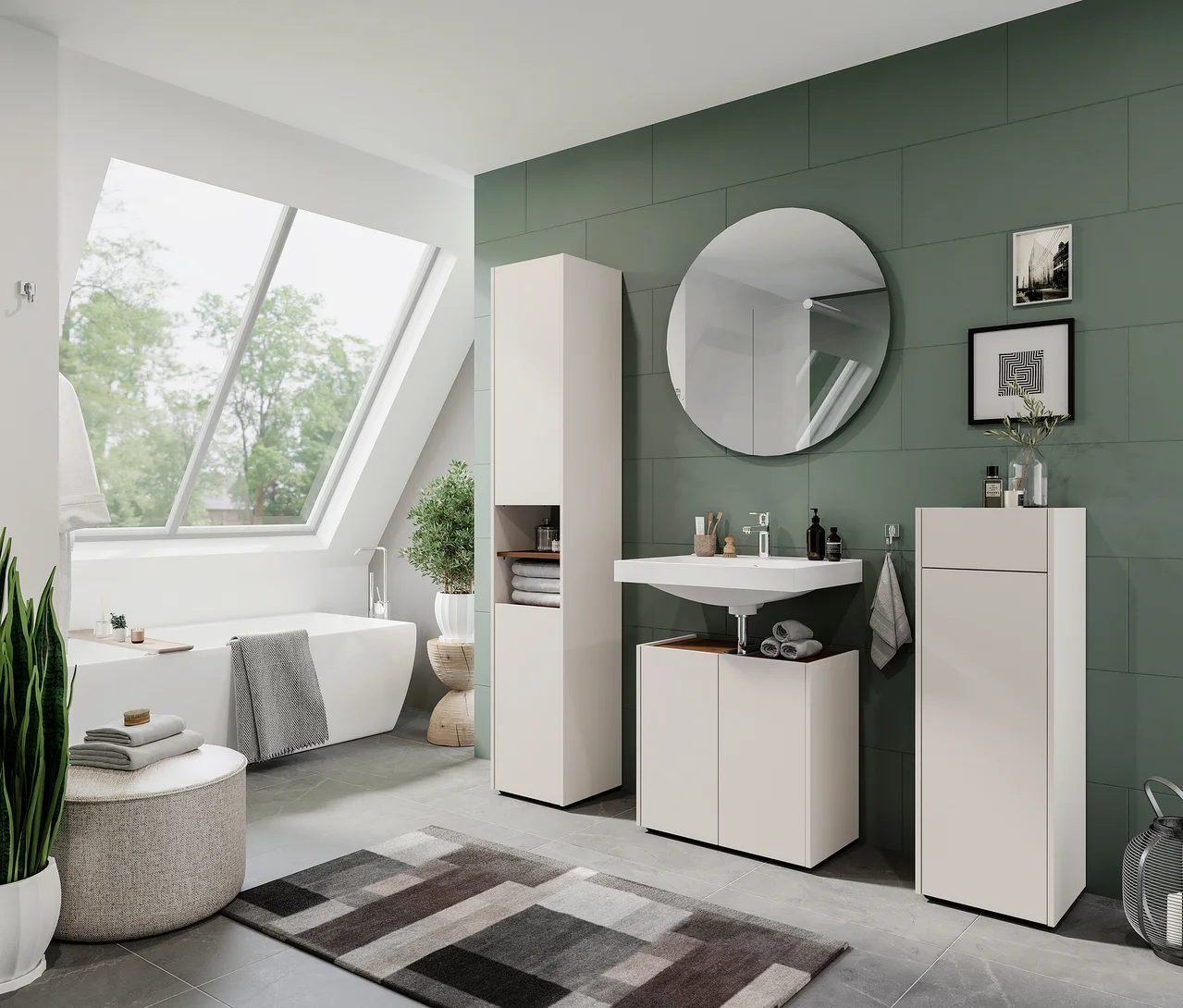 Ein modernes Badezimmer mit einer weißen Badewanne unter einem großen Dachfenster. Eine grün geflieste Wand zeigt ein weißes Waschbecken mit einem runden Spiegel darüber, flankiert von hellbeigen Schränken. Unter dem Waschbecken steht ein Waschbeckenunterschrank »Wadena« in Kaschmir/Nussbaum, auf dem gefaltete graue Handtücher liegen. Ein grauer Teppich mit geometrischem Muster liegt auf dem Boden, und eine Topfpflanze steht neben der Wanne.