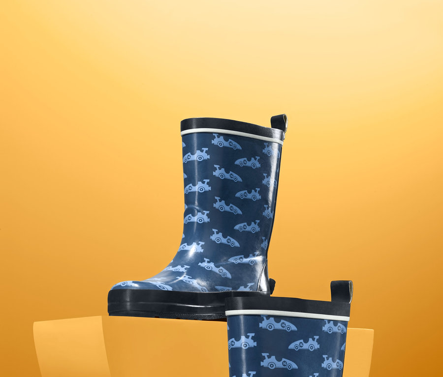 Zwei blaue Regenstiefel mit Muster auf orangem Hintergrund.