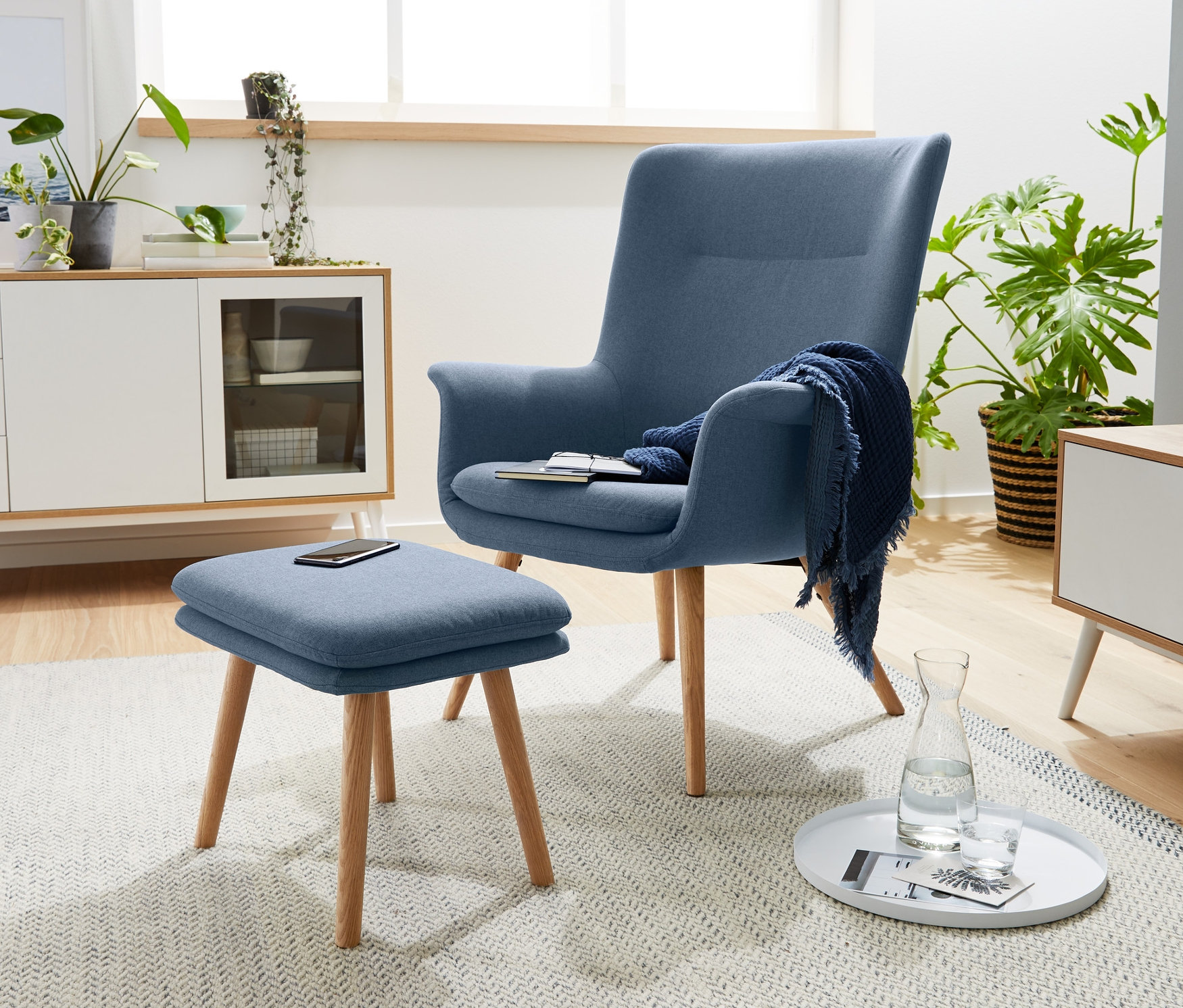 Blauer Sessel mit Fußhocker steht im Wohnzimmer.