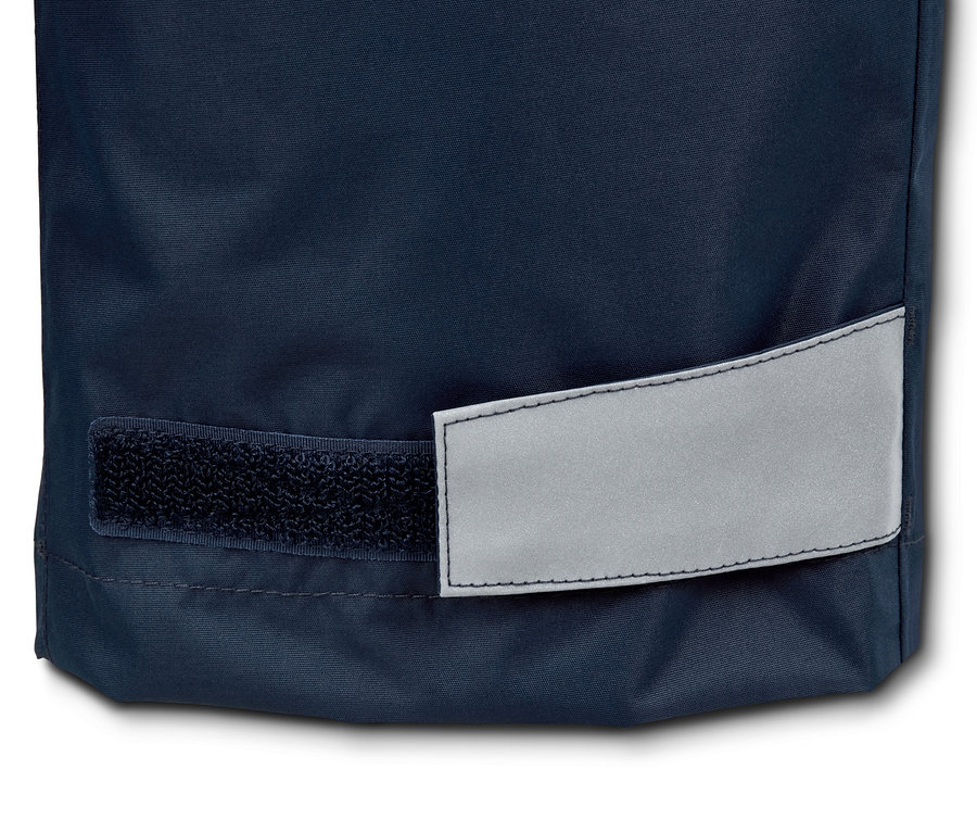 Detailaufnahme vom Beinabschluss einer Regenhose aus recyceltem Material mit Reflektor und Klettverschluss.