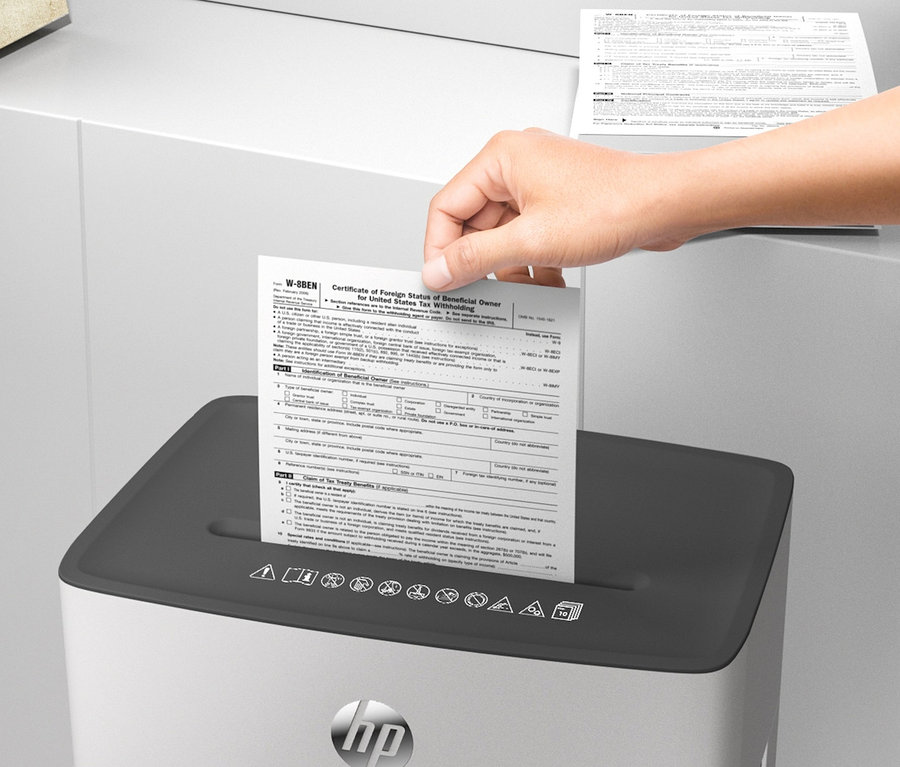 Eine Hand legt ein Dokument in den HP-Aktenvernichter »OneShred 10MC«.