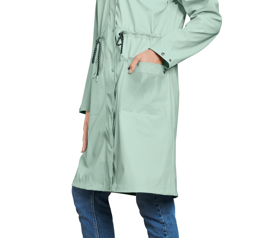 Frau trägt einen Regenparka und hat eine Hand in der Tasche.