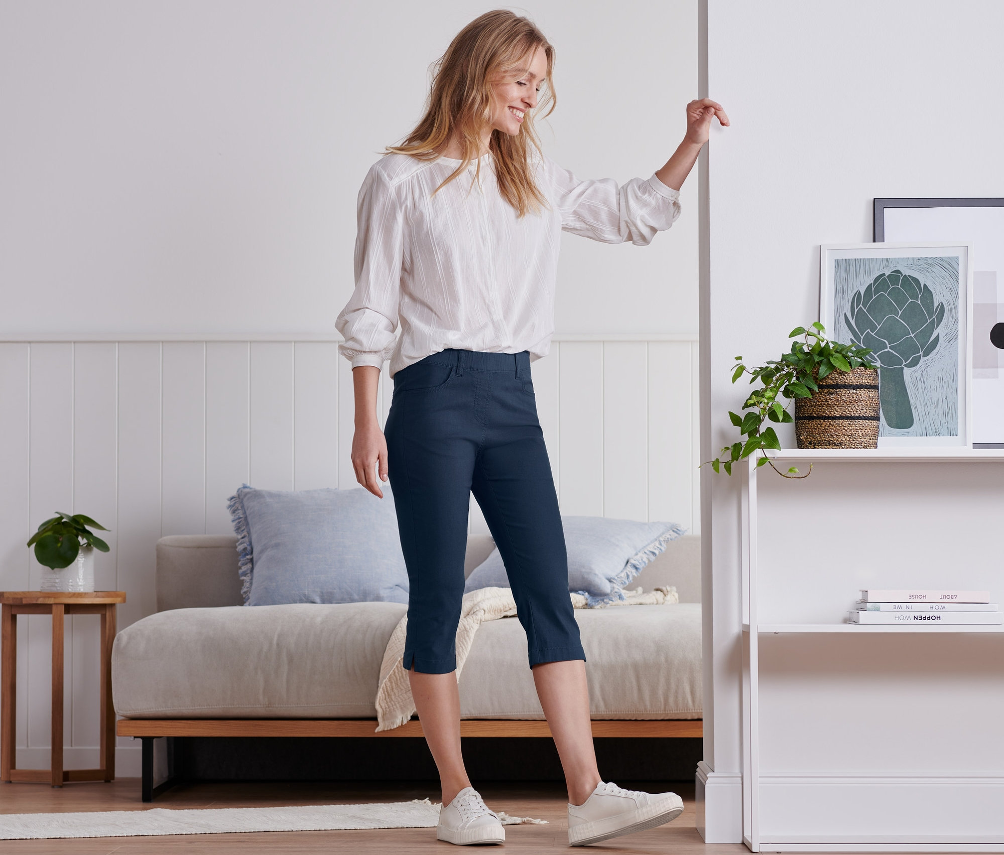 Eine Frau steht in einem Raum und trägt eine dunkelblaue 3/4-Bengalin-Hose.