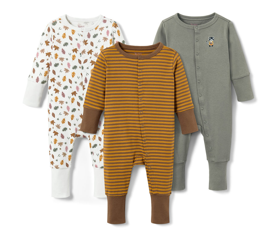Drei Baby-Schlafanzüge: ein weißer mit Blättermuster, ein braun-gelb gestreifter und ein graugrüner mit Tier-Applikation.