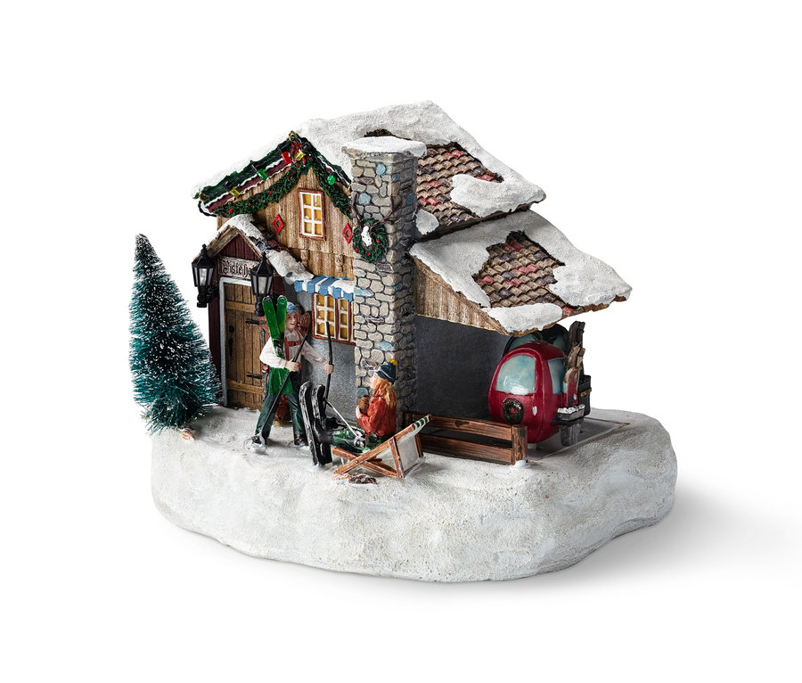Beleuchtetes Luville – Ski-Hotel Modell mit zwei Figuren, Skilift und verschneiter Landschaft.