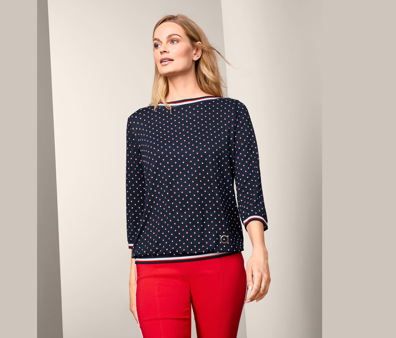 Frau trägt ein Blusenshirt mit 3/4-Arm und eine rote Hose.