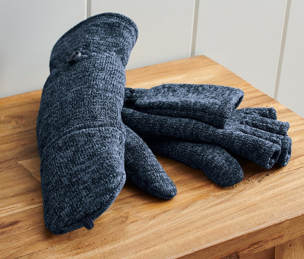 Ein Paar blaue Strickfleece-Klappfäustlinge liegen auf einer Holzbank neben einer blauen Tasche.