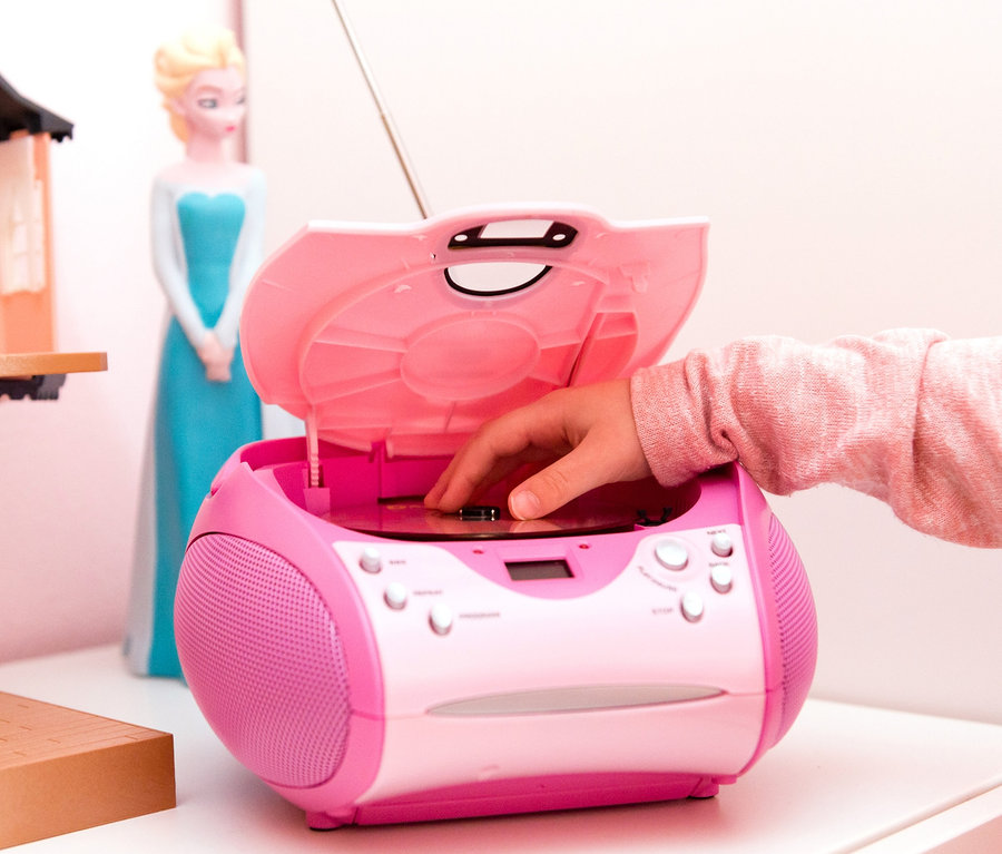 Kinderhand legt CD in pinkfarbenen Lenco Boombox neben Elsa-Puppe und Puppenhaus.