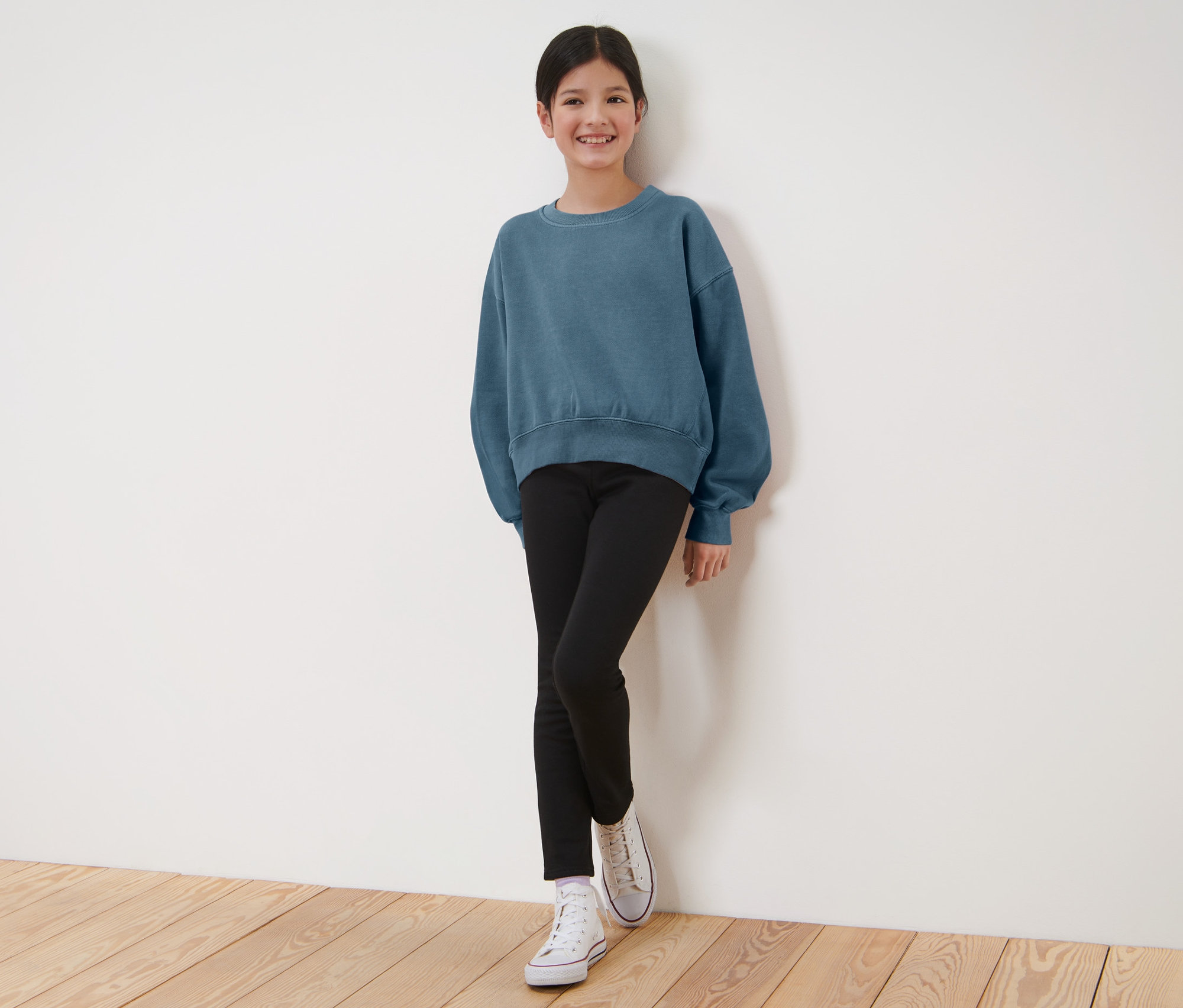 Mädchen in blauem Sweatshirt und schwarzen Kinder-Thermoleggings.