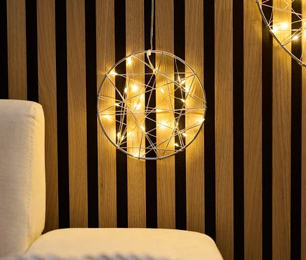 Zwei kleine LED-Kreise hängen an einer Holzwand über einem Sofa.
