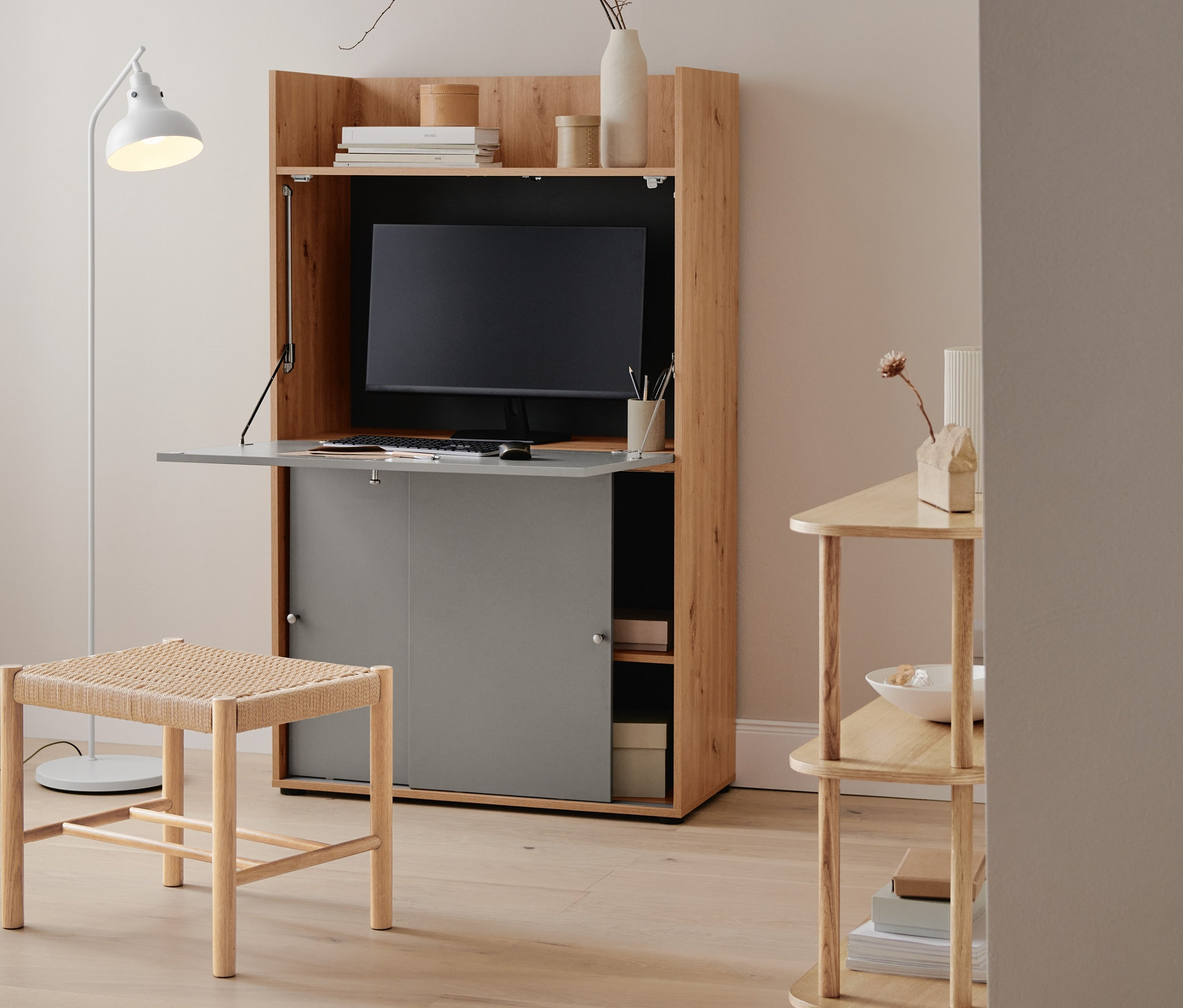 Eine Stehleuchte aus Metall steht neben einem Büroschrank mit Arbeitsfläche.