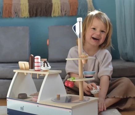 Lächelndes Kind spielt mit dem hölzernen Eisstand "small foot Eistheke »fresh«".